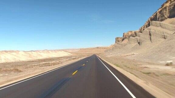 FPV:驾驶沿着空的道路通过灰色的沙漠峡谷在犹他州美国
