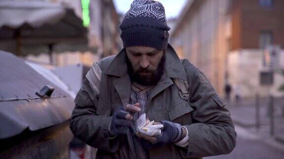 一个乞丐在垃圾堆里找到了一个三明治饥饿贫穷绝望