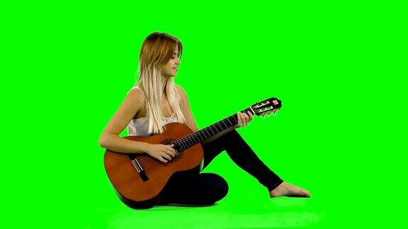 年轻美丽的白人女子在随意弹吉他绿屏