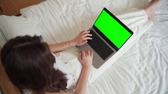 近景:聪明的白人少女用手提电脑绿屏色度键女人用触摸屏在键盘上打字网上购物浏览互联网发短信社交媒体打论文学生大学文凭网上课程的比较