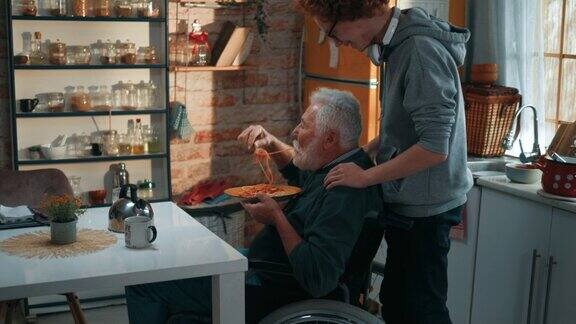 一位残疾老人在家吃午饭他的小孙子照顾他