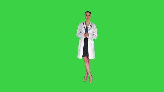 年轻的职业女医生穿着制服听诊器对着绿屏上的摄像头说话