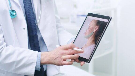 整形整容外科医生手持数字平板电脑屏幕上显示了各种类型的面部拉皮前额拉皮颧骨和鼻子矫正程序可供女性使用