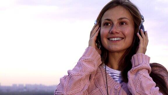 快乐的女孩站在屋顶上戴着耳机听音乐