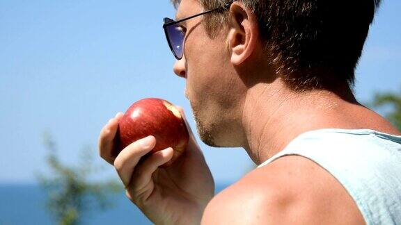 一个男人正在吃一个红苹果