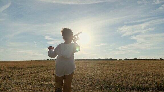 小男孩手里拿着玩具飞机在田里奔跑