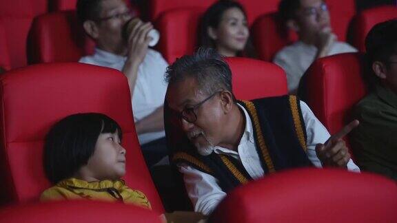 一位活跃的亚洲华人老人和他的孙女喜欢在电影院看电影