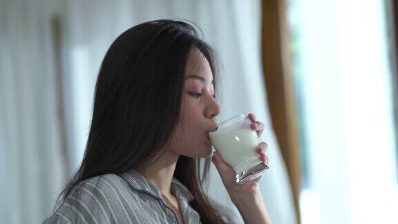 面部表情由年轻女子在纯净的早晨时间喝牛奶舔嘴唇