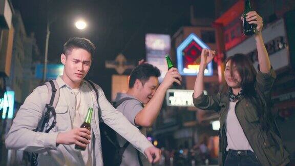 一群亚洲人在一起喝酒、喝酒、开派对年轻的男人和女人在城市旅游旅游在假期一起在黑暗的夜晚拿着啤酒在路上