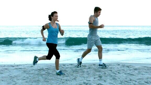 一对情侣在沙滩上跑步