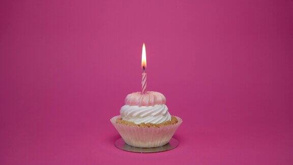 生日纸杯蛋糕与蜡烛和生日装饰在粉红色的背景