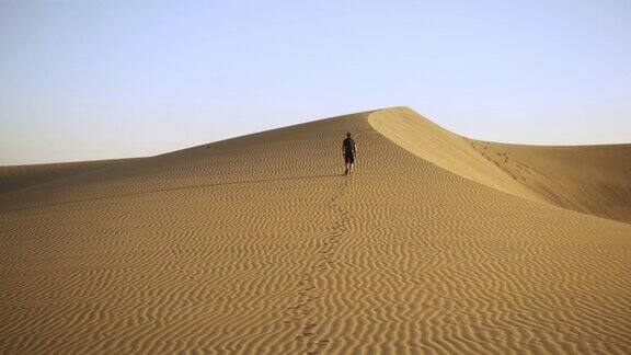 一个人走到波纹沙丘的顶部