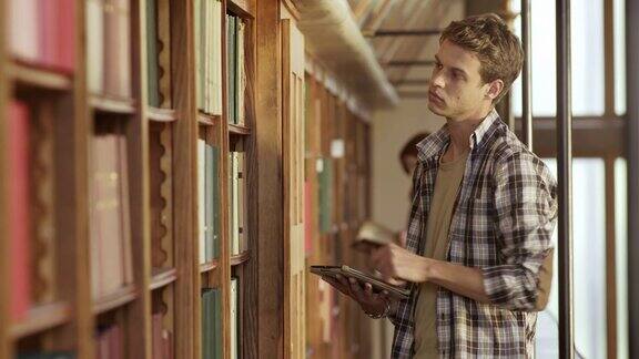 一个年轻人在图书馆里用平板电脑找书