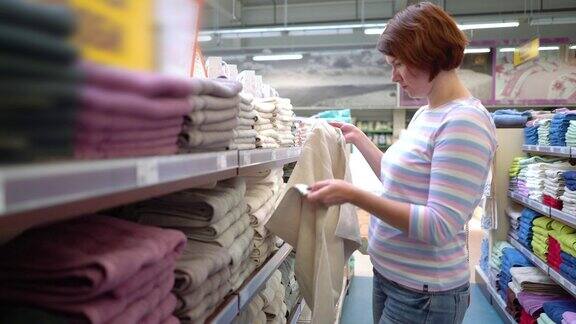 白人妇女在商店货架旁选择毛巾