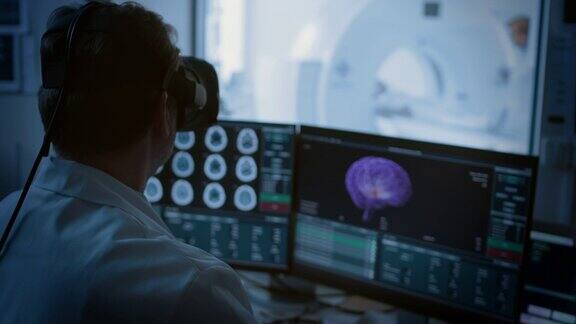 未来:在医疗控制室医生戴着虚拟现实头戴式耳机监测接受核磁共振或CT扫描的病人电脑显示可能患有癌症的3D大脑模型