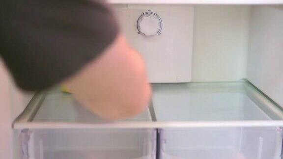 一个男人用一只黄色的海绵手清洗冰箱