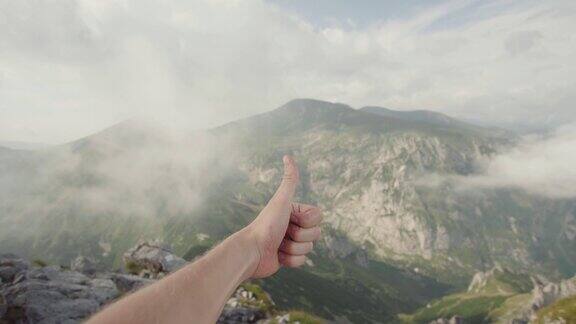 一个人在山顶举起手竖起大拇指