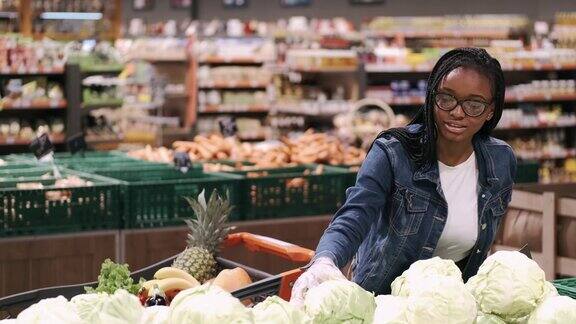 一位戴着面具的非洲裔美国妇女正在超市选购商品