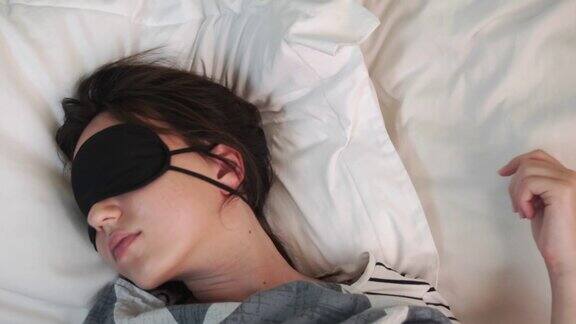 平静的年轻女子在床上休息时戴着睡眠面具从以上观点