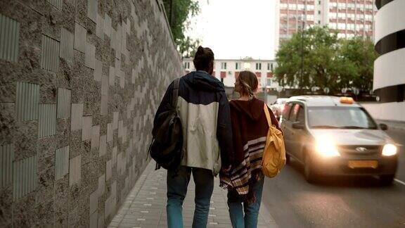 一对美丽的年轻夫妇晚上在城里散步学生们一男一女背着背包走在交通路上