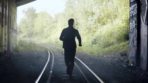慢镜头男人在铁轨上奔跑的剪影后视图抽象背景结束镜头追求自由
