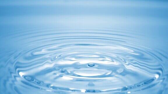 一滴水落在蓝色清澈的液体上形成圆圈