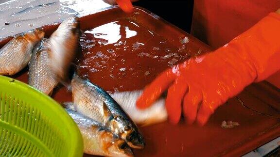 女鱼贩在鱼市场清洗和切新鲜的鱼
