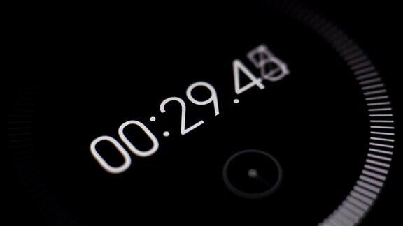 近景的黑色屏幕的数字秒表与白色运行数字时间流逝1分钟