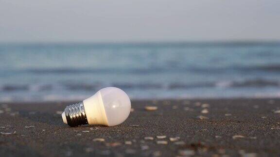 用过的led灯泡躺在潮湿的沙滩上抵御海浪