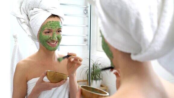 一位年轻女子用白毛巾敷着绿色保湿面膜