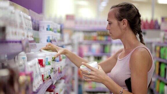 有魅力的女人在超市的化妆品区看身体护理产品
