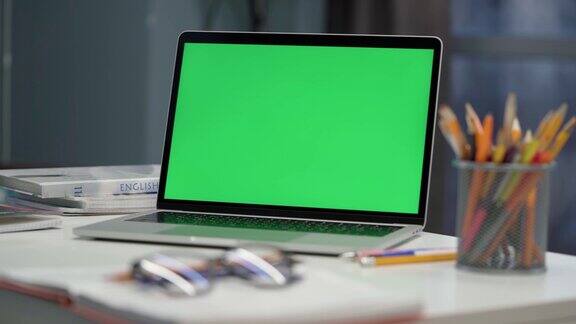 显示绿色色度键屏幕的笔记本电脑放在房间或办公室的桌子上