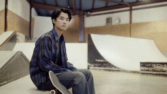 一个年轻的日本男性滑板爱好者在滑板公园的肖像(慢镜头)