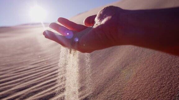干热的沙漠沙子从女性手中流淌