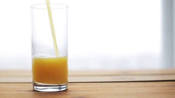 橙汁倒进木桌上的玻璃杯里