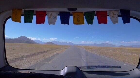 特写:透过一辆汽车的后窗可以看到西藏一条空旷的道路