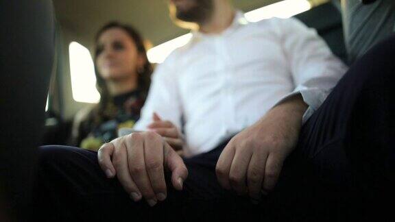 年轻夫妇在后座上开车时手牵手相爱