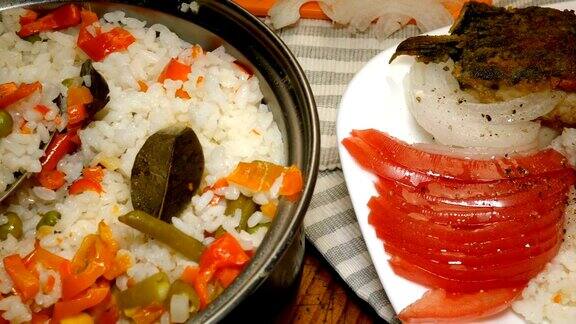 厨房木板上的白盘子里放着热米饭、切好的西红柿和洋葱片