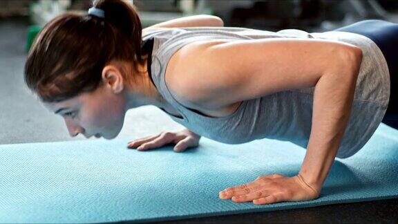 年轻女子在健身房的健身垫上做俯卧撑