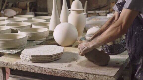 一名中年男子在作坊里用手捏粘土这是制陶的前一步