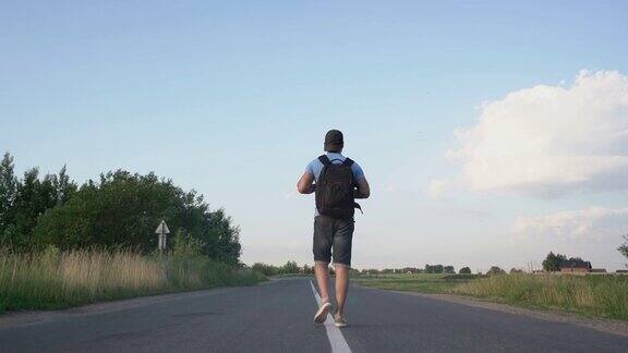 背着背包的男子走在城外的道路中心的后视图