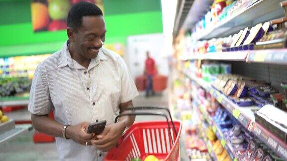 成熟的男人在超市购物用智能手机扫描条形码