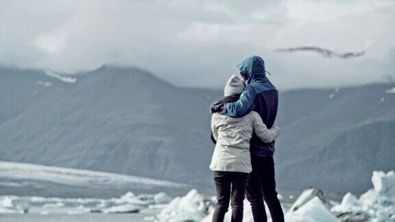 一对情侣拥抱着看着冰川泻湖