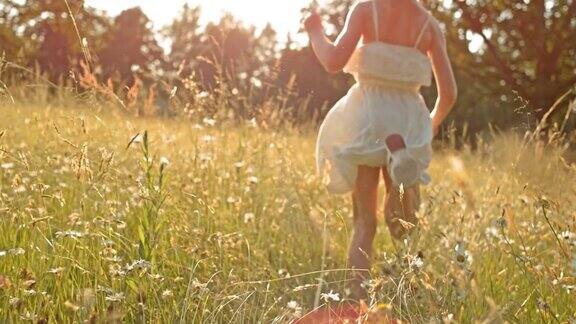 SLOMOTS女孩在阳光下穿过高草