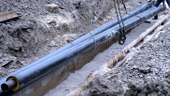 工人们用建筑起重机把管道埋在地下