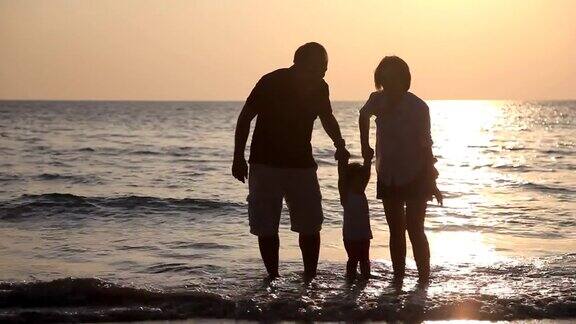 日落时分一家人在海滩上玩耍放松