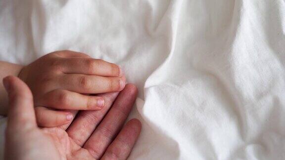 孩子和妈妈的手放在白色的床背景上