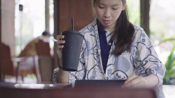 年轻的亚洲女性用环保可重复使用的咖啡杯喝水