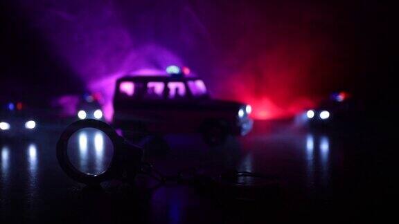 警方夜间突袭你将被逮捕手铐的剪影与警车在后面与闪烁的红色和蓝色警灯在雾蒙蒙的背景滑块拍摄