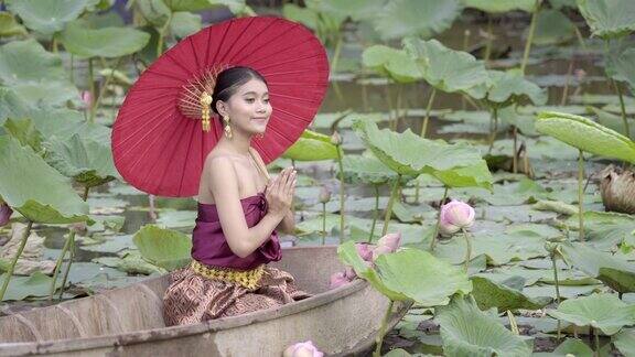 泰国妇女穿着泰国民族服饰坐在船上和莲花在泰国